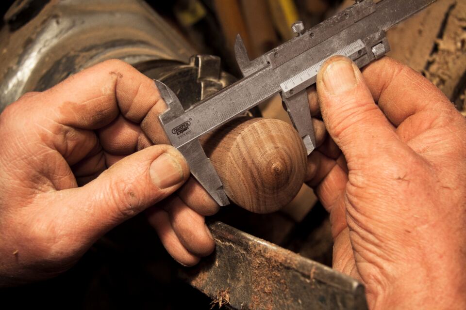 Hands measuring a part with a vernier caliper