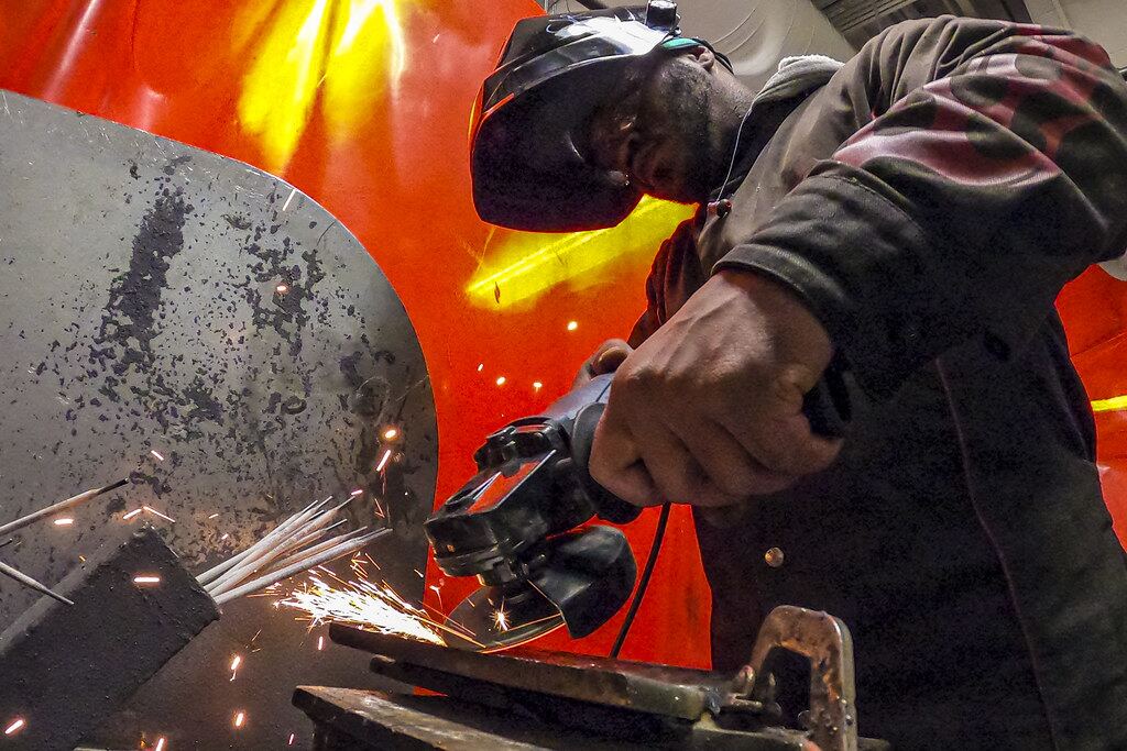 Technician grinding a metal part with sparks
